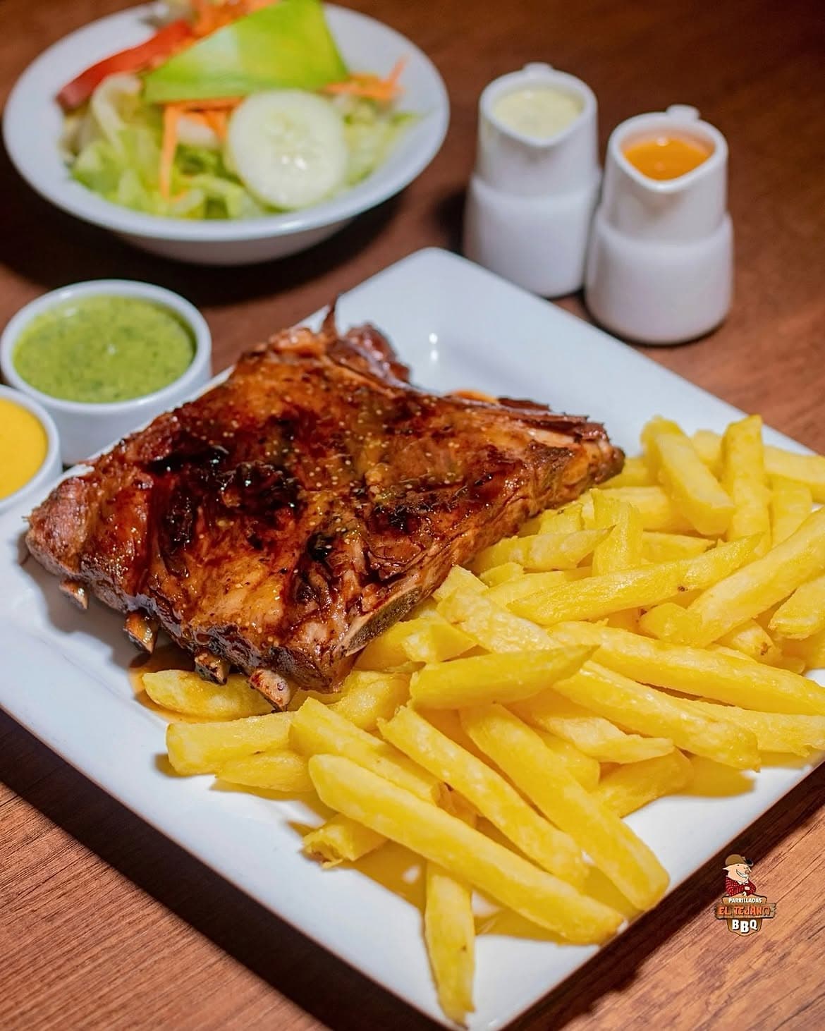 Costilla BBQ servida con papas y salsas