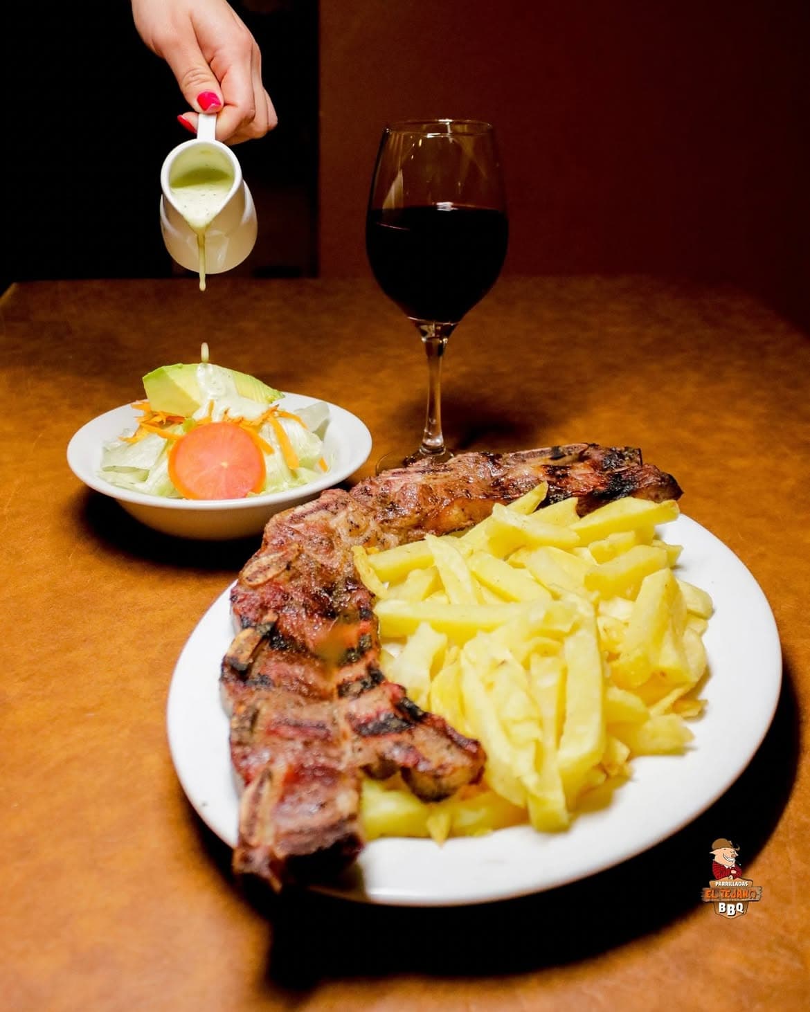 Mesa servida con chuleta, ensalada y copa de vino